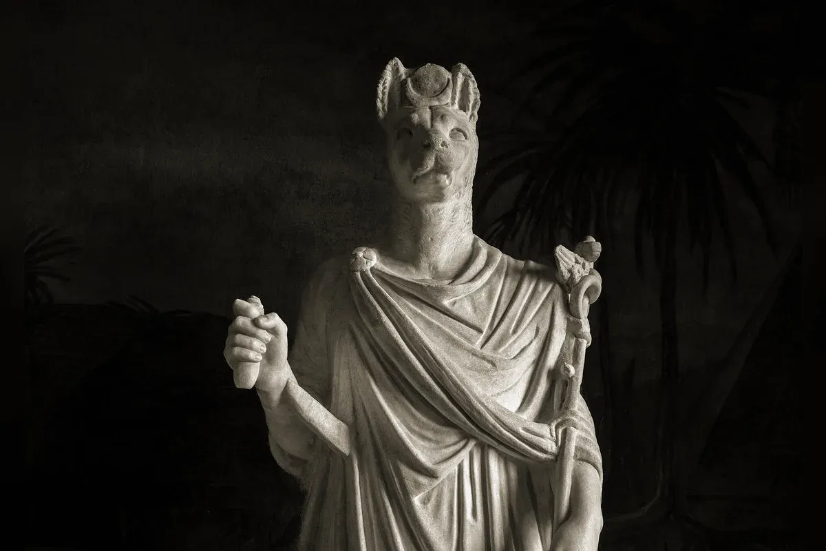 Anubis with a black jackal head, from ancient Egyptian art, watching over a mummy