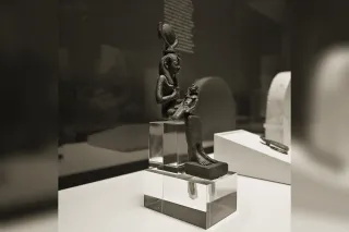 Isis with outspread wings, wearing the throne hieroglyph headdress, protecting the mummy of Osiris
